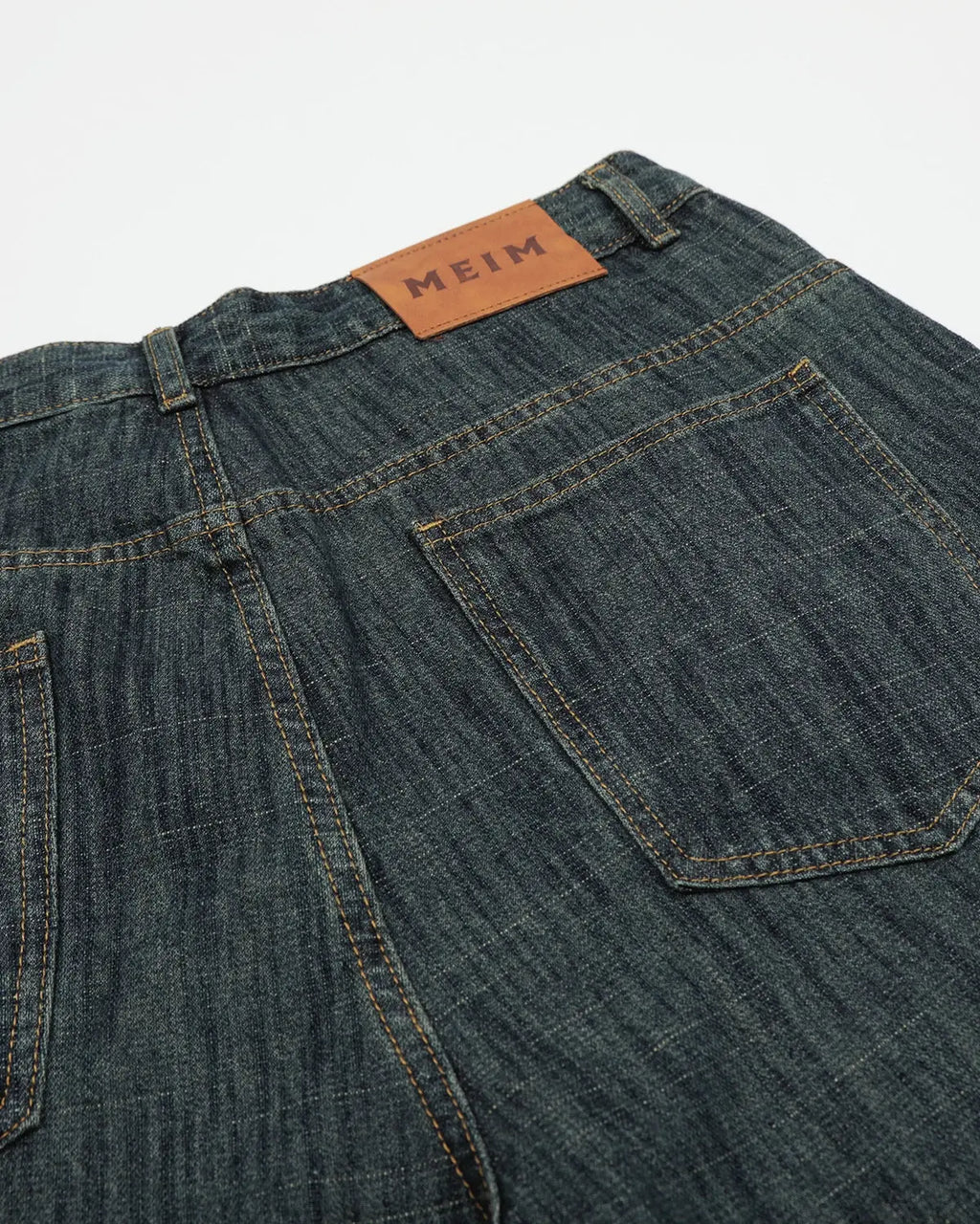 Raw wide-leg long jorts by INFLATION, denim pants featuring distressed details and a relaxed fit, shown on a hanger.