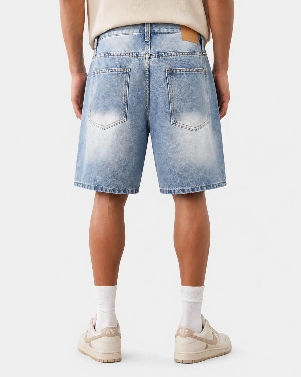 Ripped mid-length washed denim shorts by INFLATION, casual denim pants with distressed details and frayed hem.