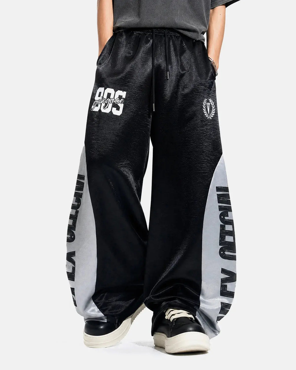 Model wearing glossy black contrast barrel sweatpants by INFLATION, featuring a relaxed fit and stylish design.