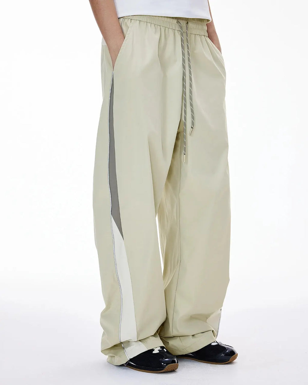 Reflective windbreaker track pants by INFLATION, featuring a sleek design and reflective details for streetwear style.