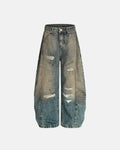 Distressed dirty wash barrel jeans by INFLATION showing frayed hems, faded denim, and relaxed fit on a model.