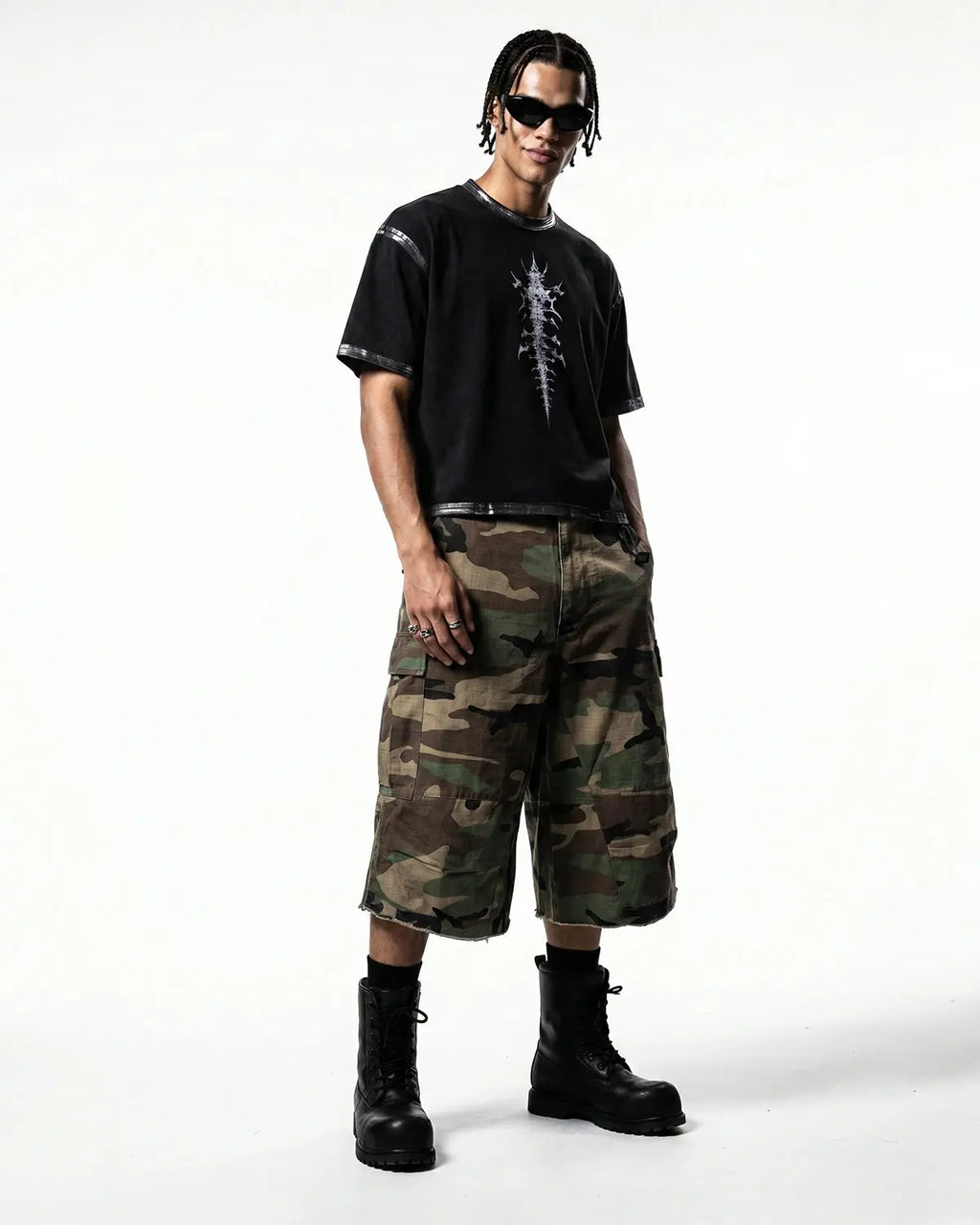 Inflation brand oversized camo cargo longline shorts with large pockets and relaxed fit, styled in green and brown camouflage pattern.
