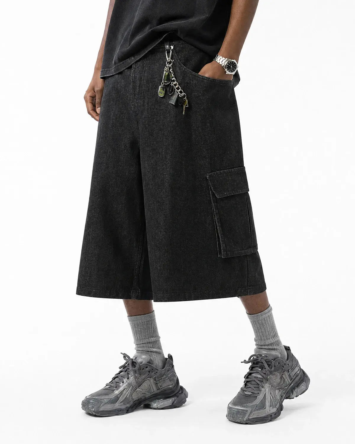 Black cargo longline jorts by INFLATION, featuring extended length, multiple pockets, and casual streetwear style.