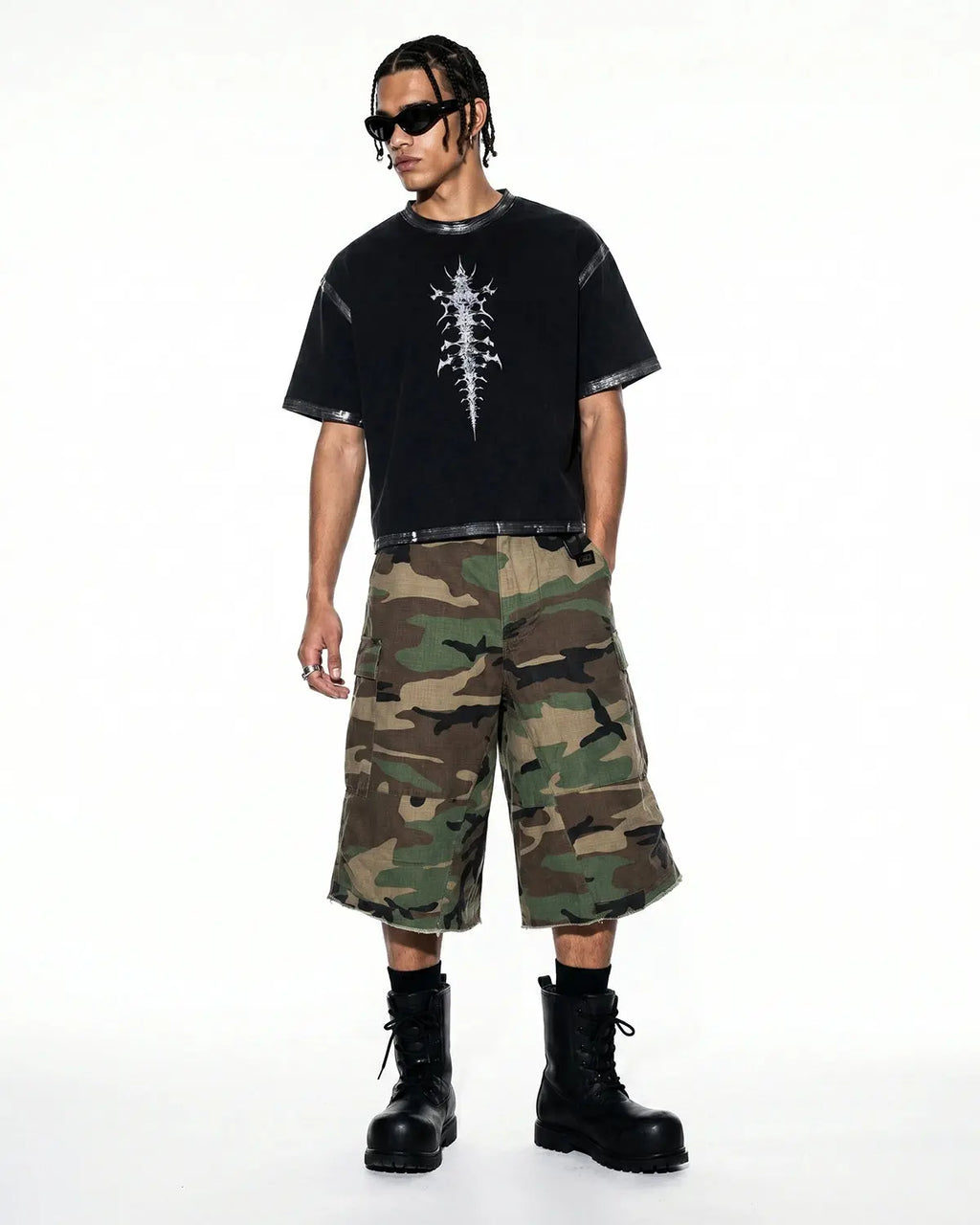 Inflation oversized camo cargo longline shorts with large side pockets and a relaxed fit, featuring green and brown camouflage pattern.