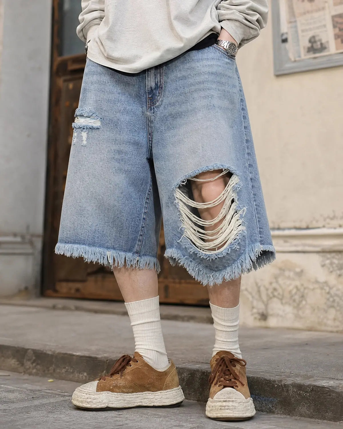 Distressed baggy jorts with adjustable waist tabs by INFLATION, featuring a relaxed fit and worn denim look.