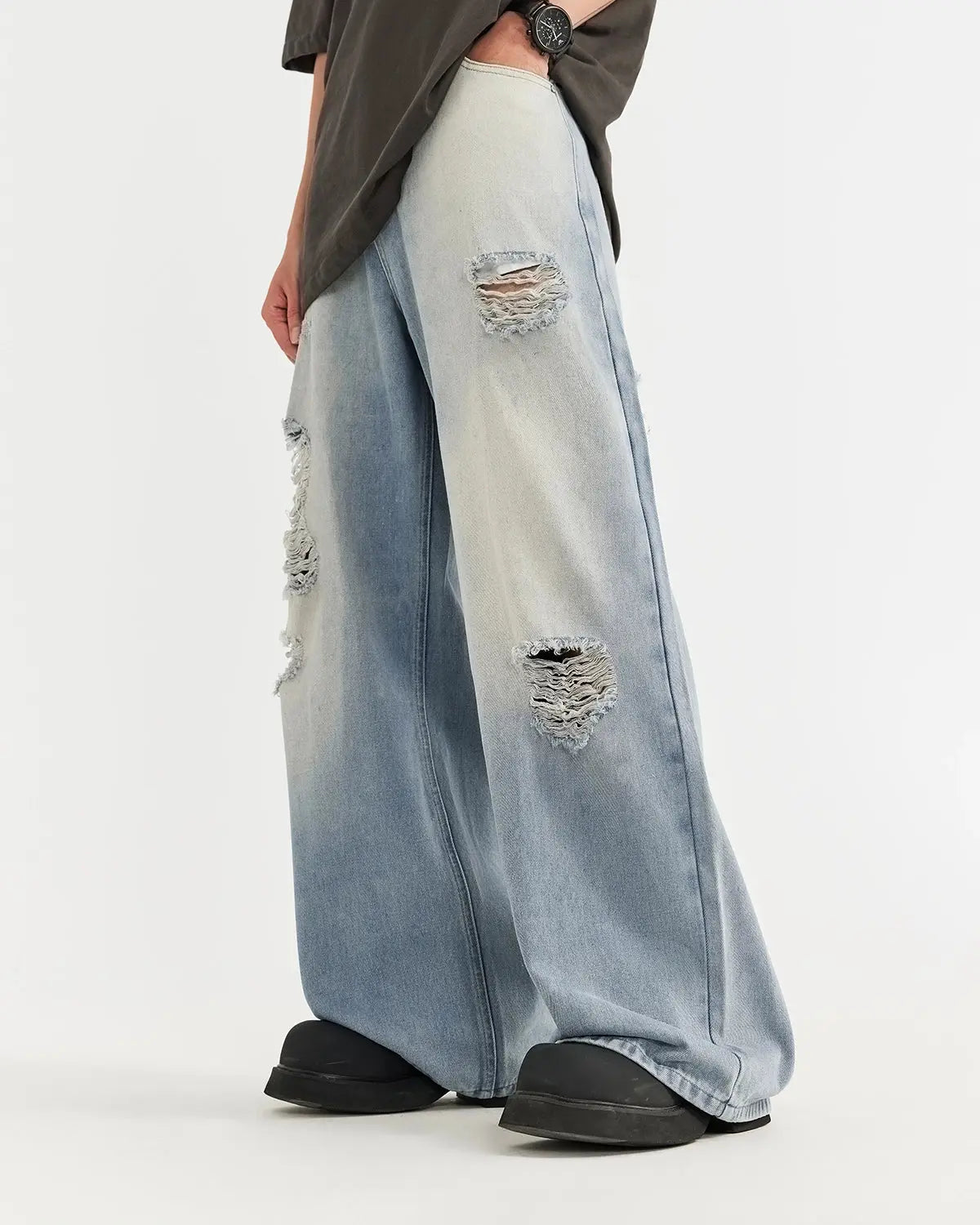 Distressed ripped blue jeans by INFLATION streetwear, featuring a casual fit with frayed holes and worn denim detailing.