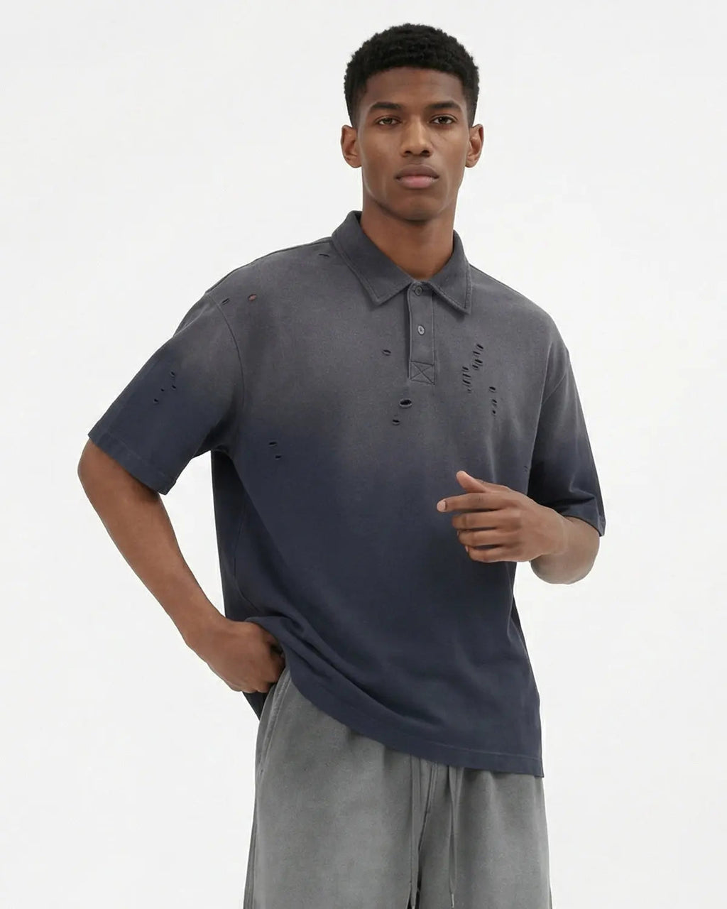 Distressed washed polo shirt by INFLATION with ripped details, casual streetwear style, shown on a hanger.