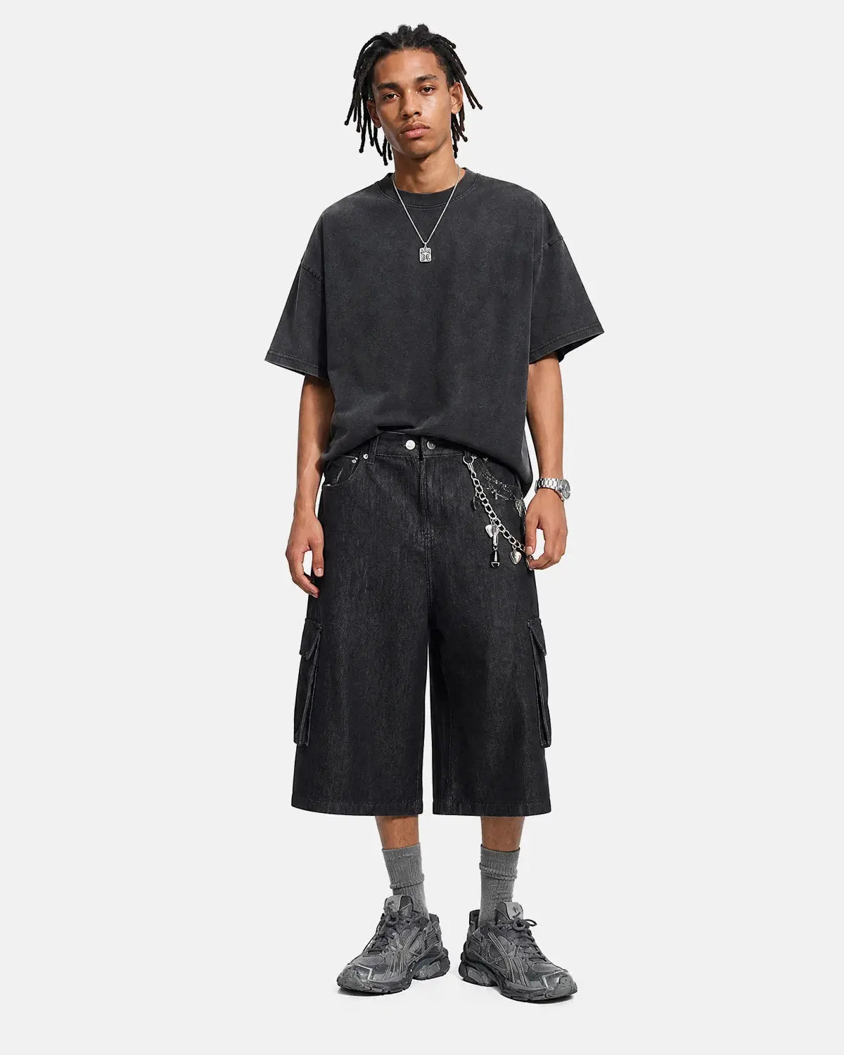 Black cargo longline jorts by INFLATION, featuring a relaxed fit with large side pockets and distressed denim details.