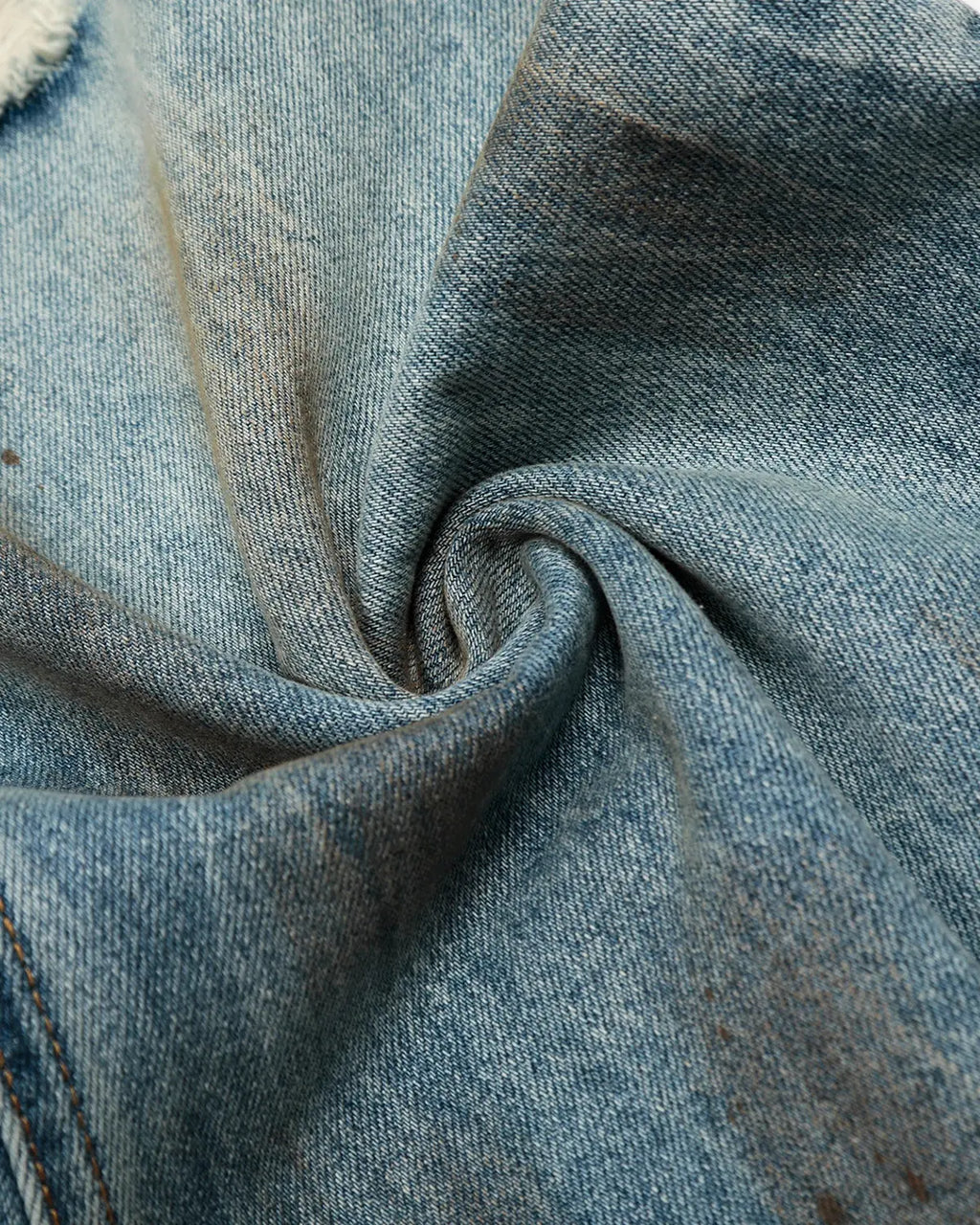 Distressed barrel jeans by INFLATION, featuring a rugged wash and distressed details, styled as streetwear on a casual model.