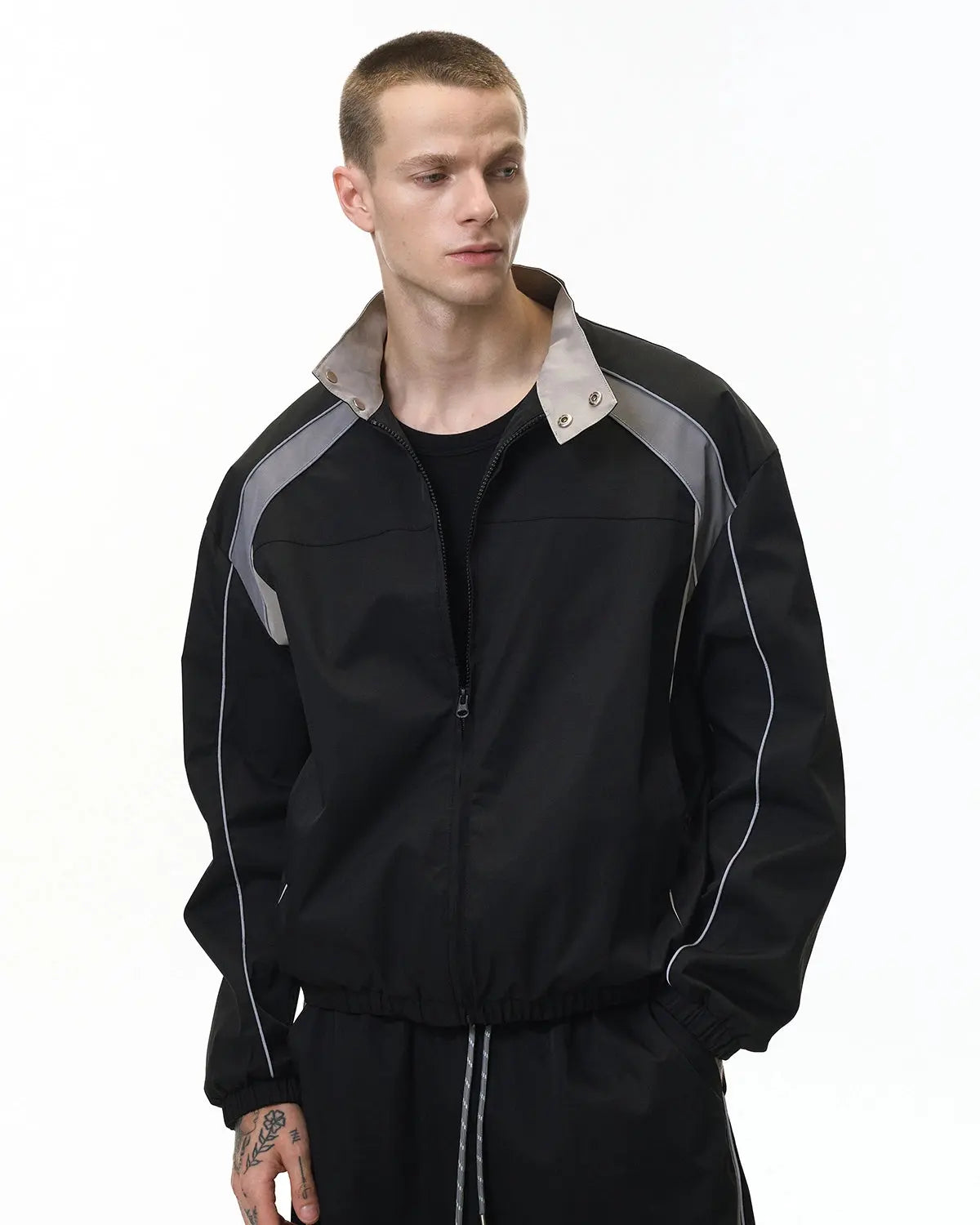 Reflective black windbreaker track jacket by INFLATION with reflective accents, lightweight design, and casual streetwear style.