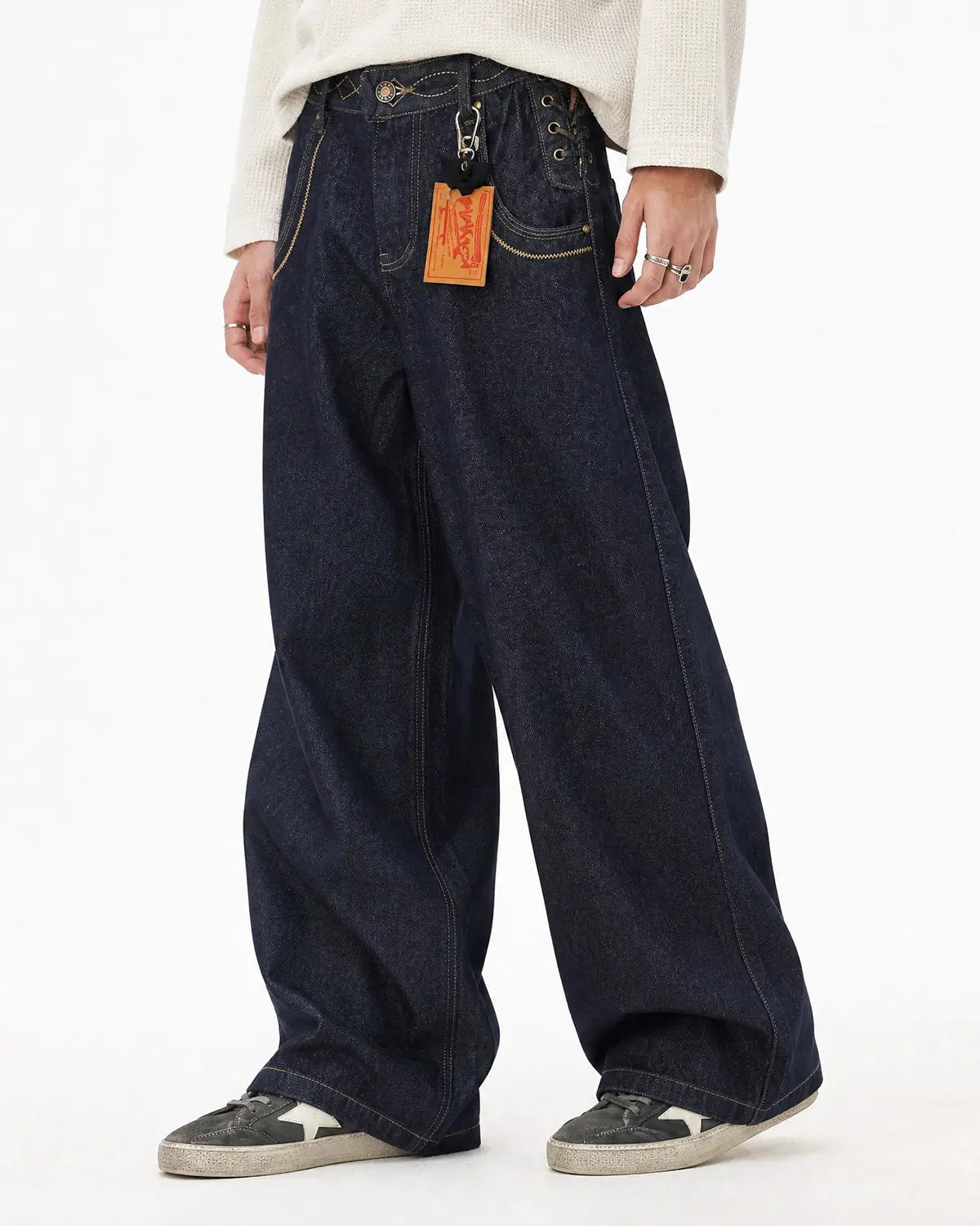 Side lace-up raw baggy jeans by INFLATION featuring a relaxed fit and streetwear style, shown in a casual pose.