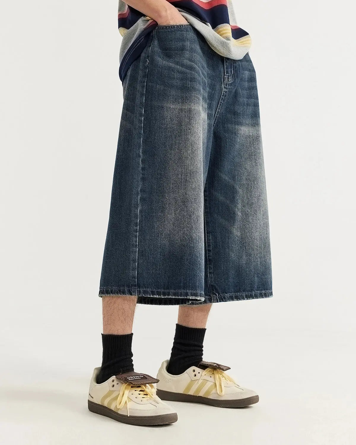 Acid washed longline baggy denim jorts by INFLATION, relaxed fit pants with distressed detailing, styled with rolled cuffs and casual look.
