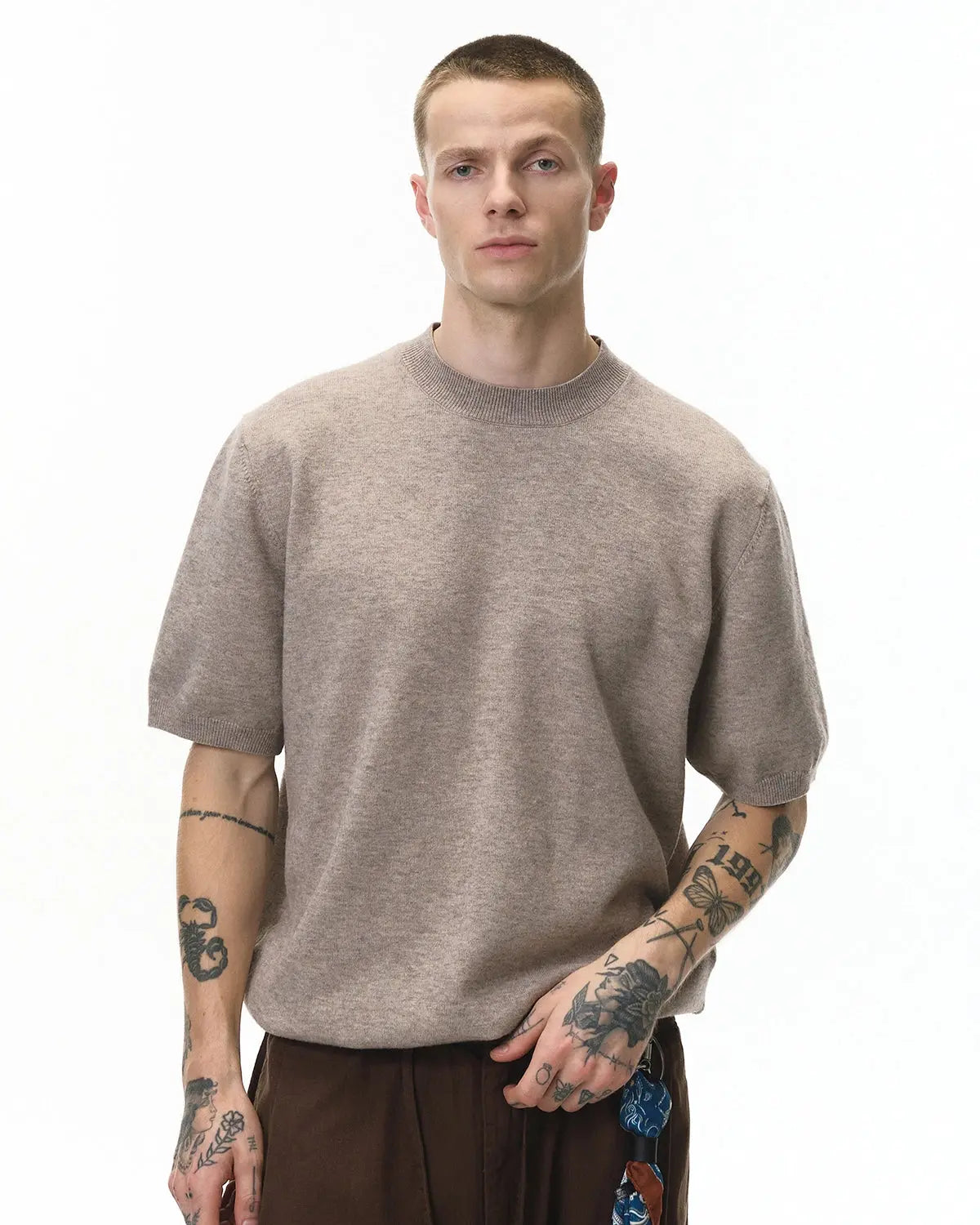 Short-sleeved crewneck sweater by INFLATION, knitted fabric, in neutral color, close-up view showing texture and fit.