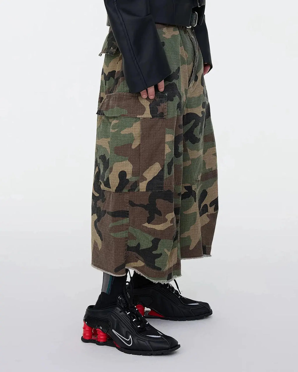 Inflation Streetwear oversized camo cargo longline shorts with large side pockets and relaxed fit, in green and brown camouflage pattern.
