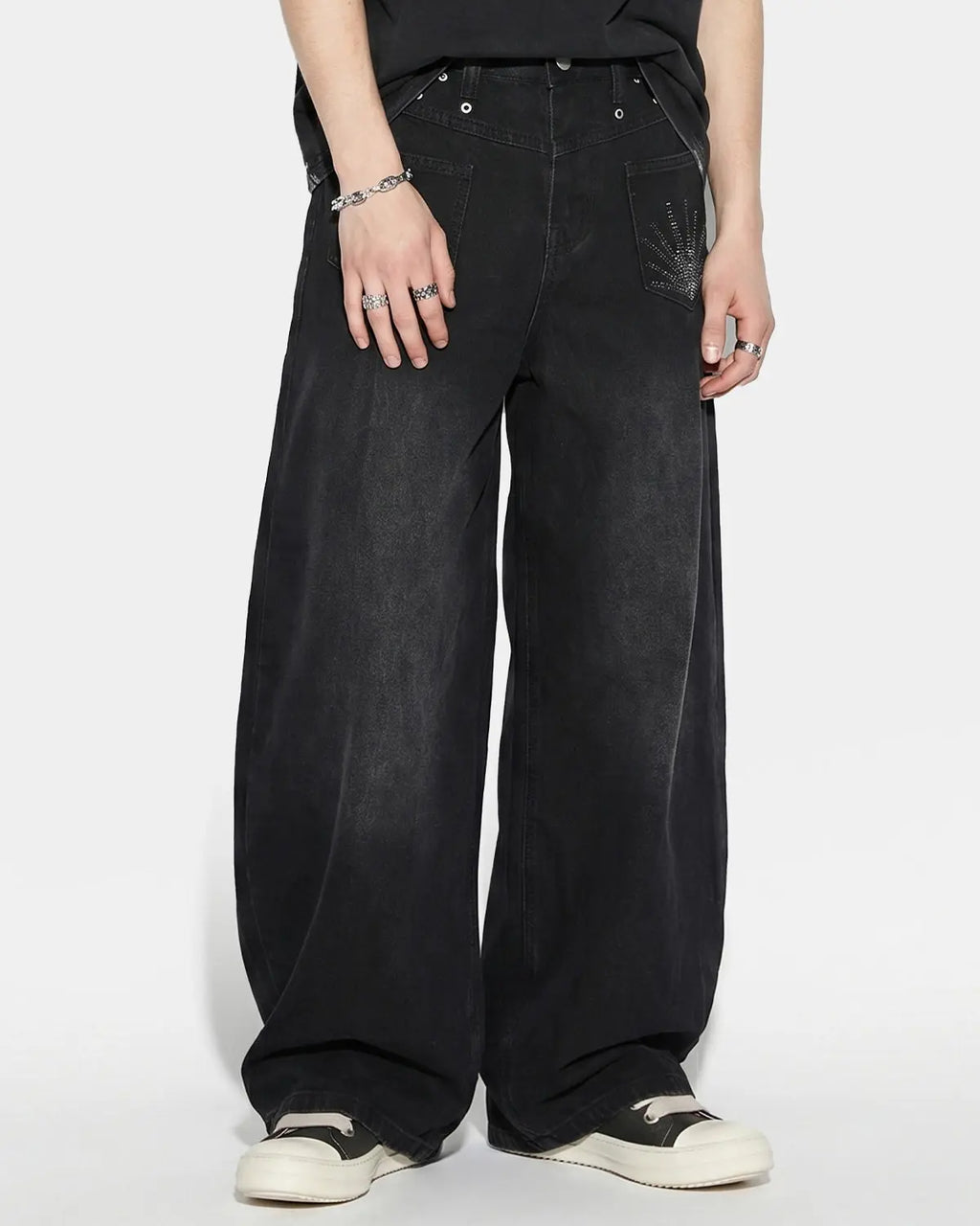 Distressed eyelet barrel jeans by INFLATION featuring a relaxed fit and eyelet details, shown on a model.