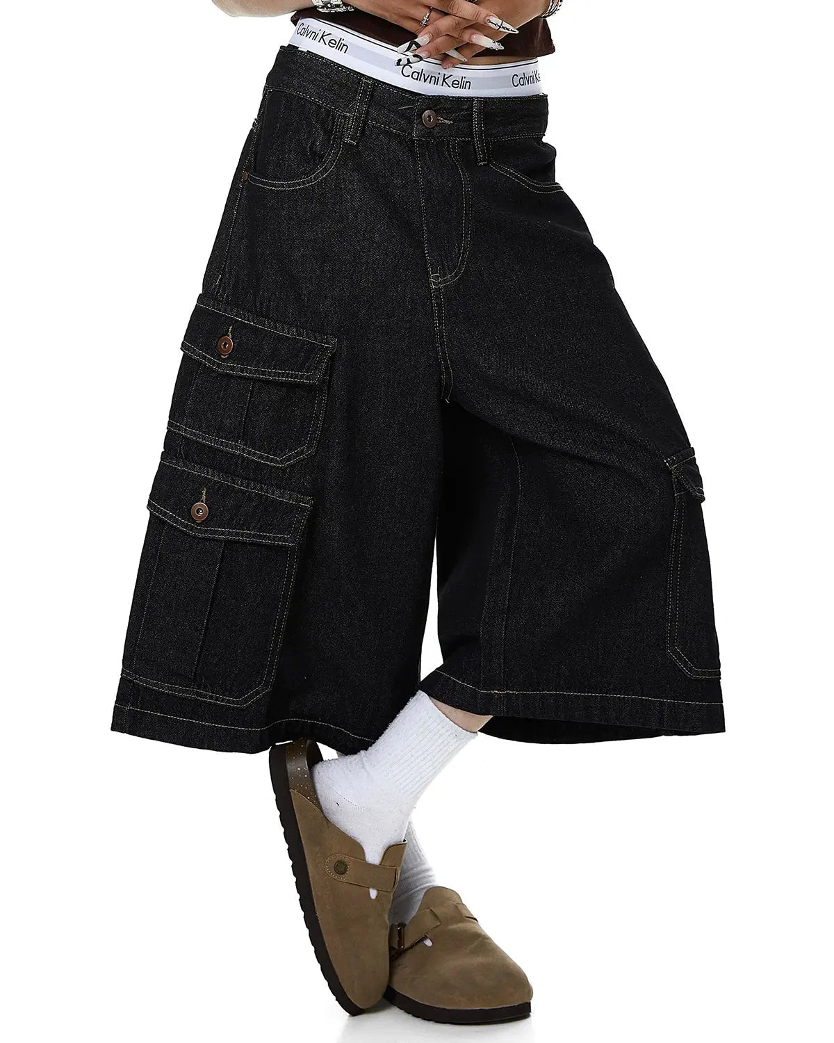 Raw denim longline cargo jorts by INFLATION featuring multiple pockets and a relaxed fit on a model.