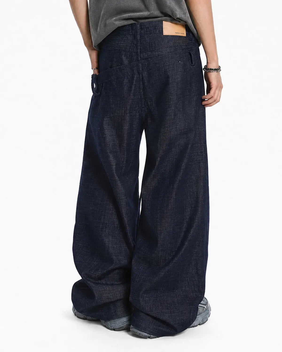 Inflation asymmetric wrap waist baggy jeans showcasing relaxed fit, distressed denim, and unique wrap detail on a model.