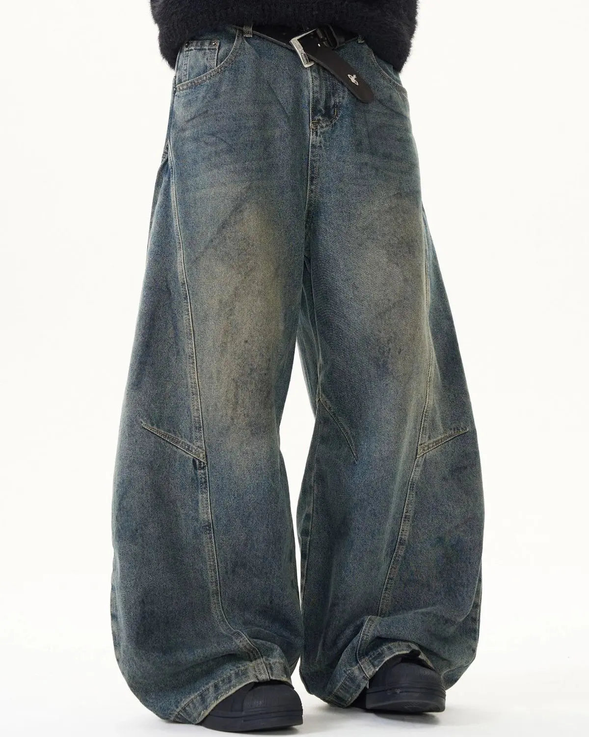 Washed deconstructed barrel jeans by INFLATION, streetwear style with distressed details and relaxed fit, shown on a model.