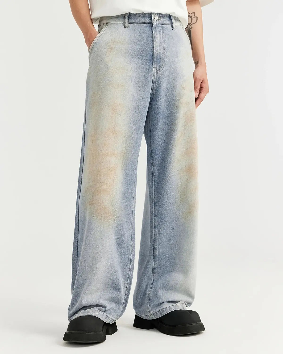 Mud Washed Baggy Jeans by INFLATION, relaxed fit denim with a distressed, muddy wash finish, displayed on a hanger.