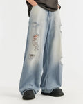 Distressed ripped blue jeans by INFLATION, featuring a casual fit with frayed holes and worn denim for streetwear style.