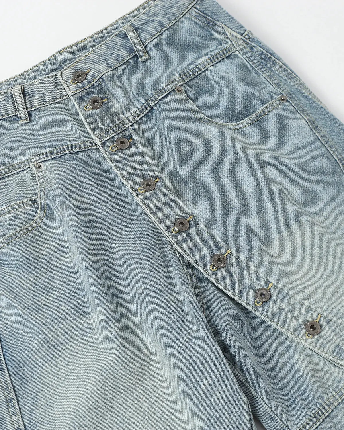 Asymmetric button detail on Inflation Streetwear baggy jeans featuring a relaxed fit and stylish streetwear design.