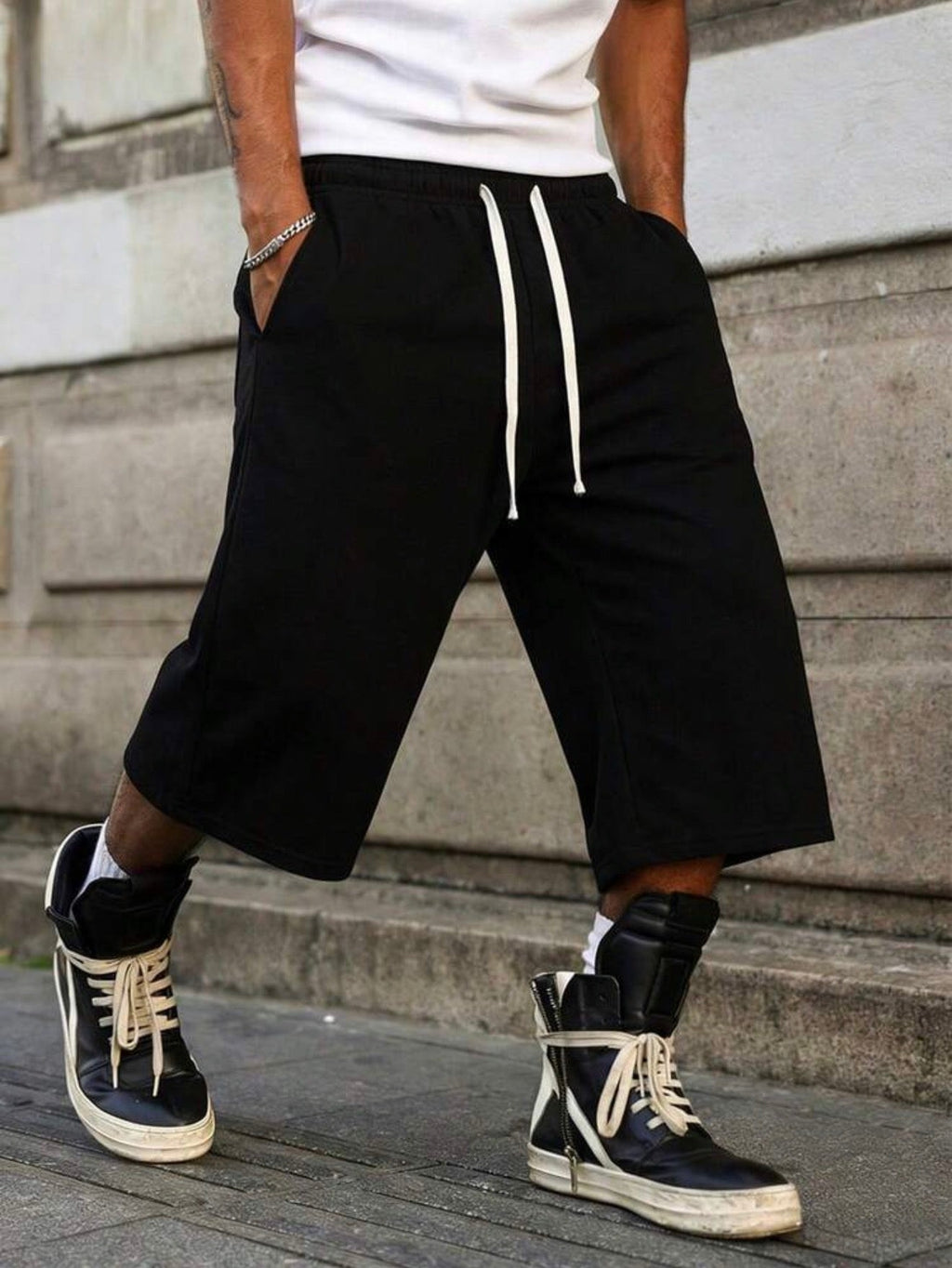 Inflation trending long jogger shorts in black with drawstring waist, relaxed fit, and cuffed hems, suitable for casual wear.