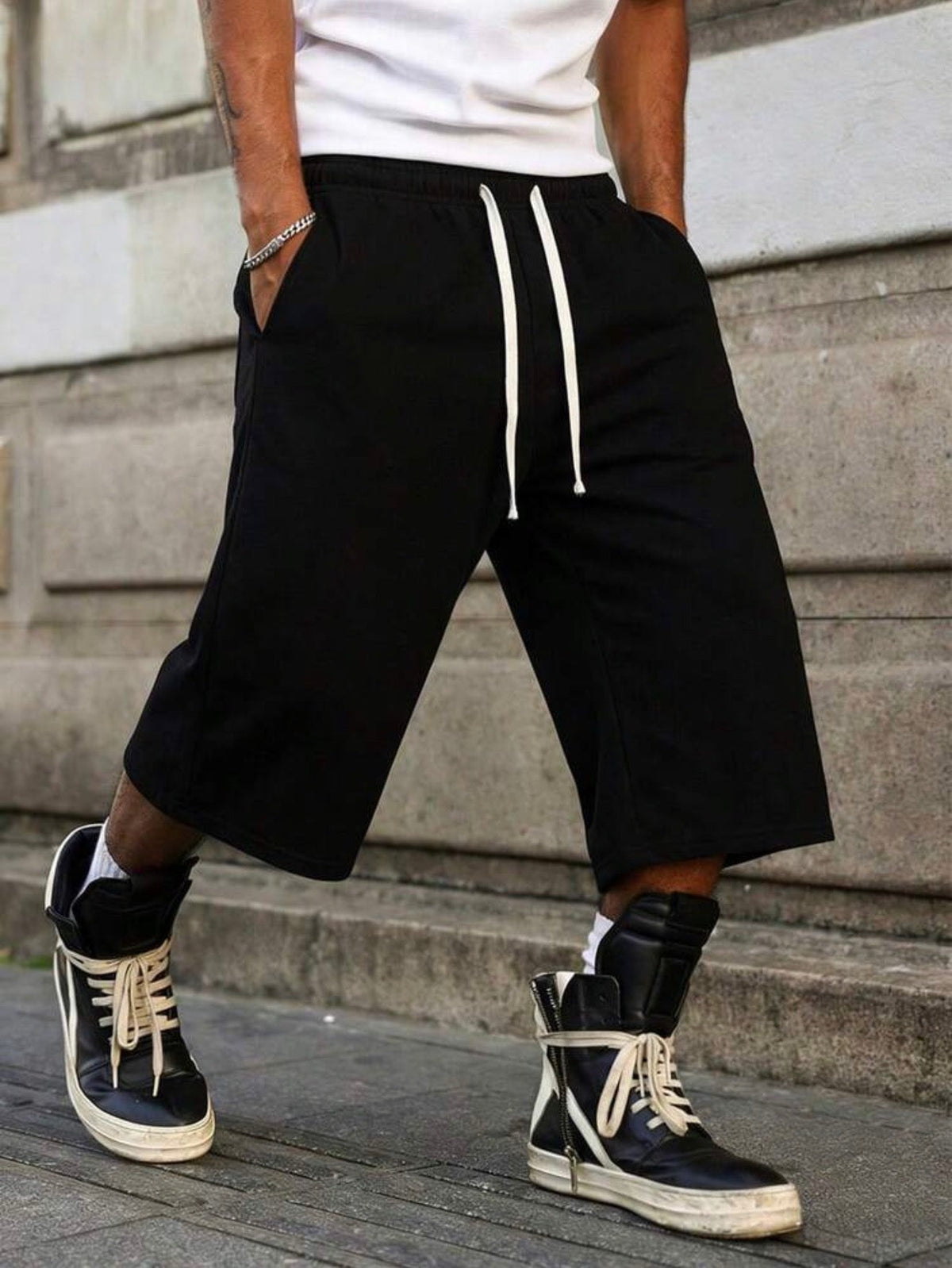 Inflation trending long jogger shorts in black with drawstring waist, relaxed fit, and cuffed hems, suitable for casual wear.
