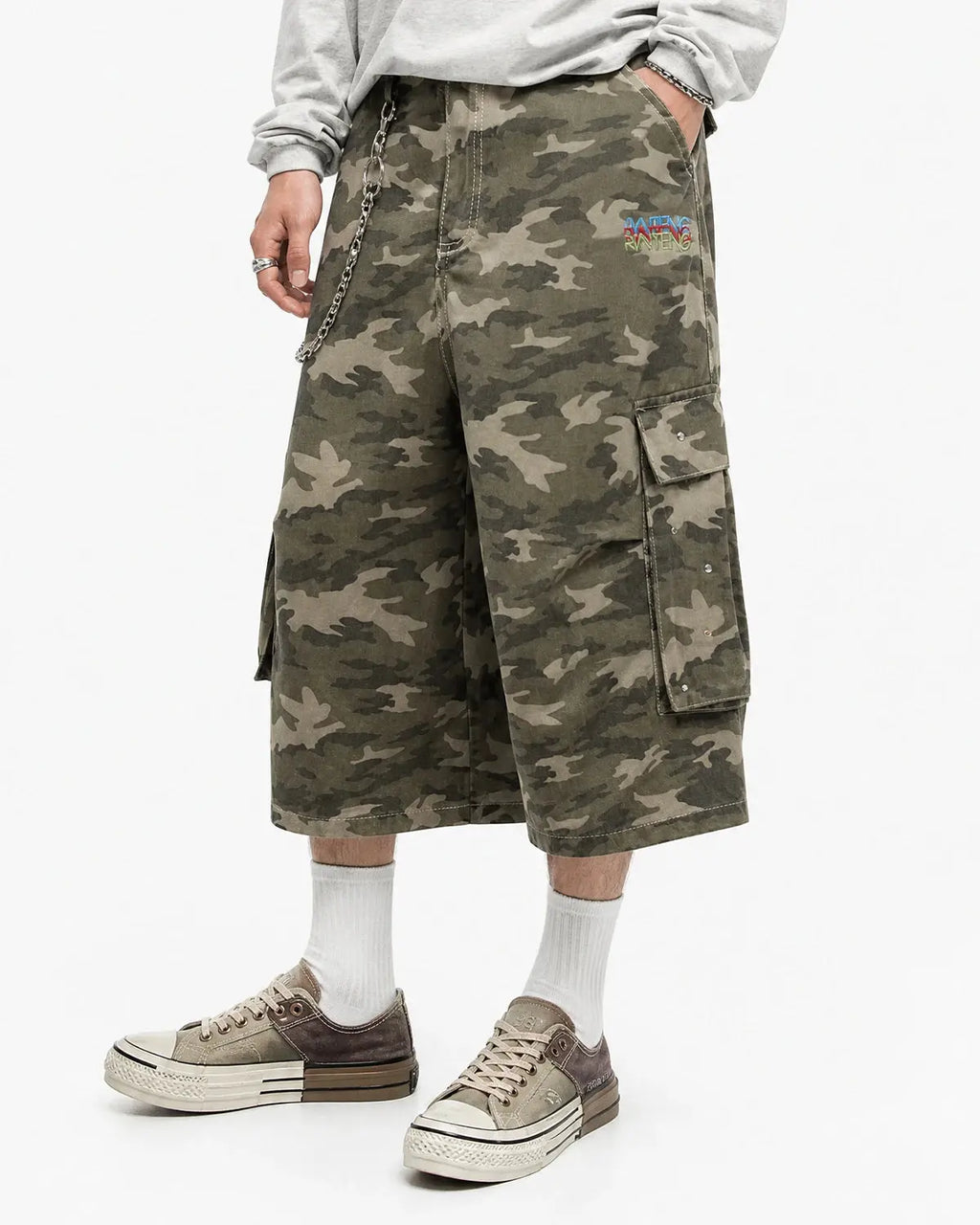 Embroidered camo cargo longline shorts by INFLATION, featuring tactical pockets and a relaxed fit, styled with streetwear details.