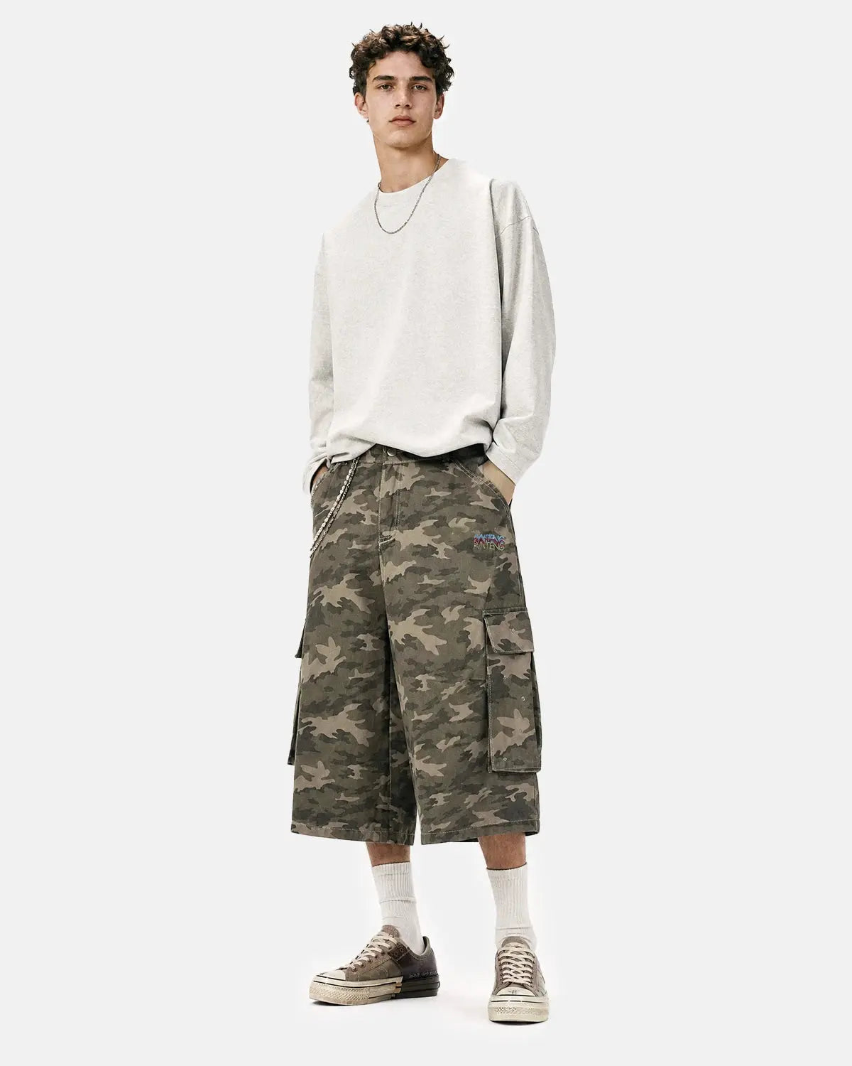 Embroidered camo cargo longline shorts by INFLATION, featuring a military-inspired camouflage pattern and multiple utility pockets.